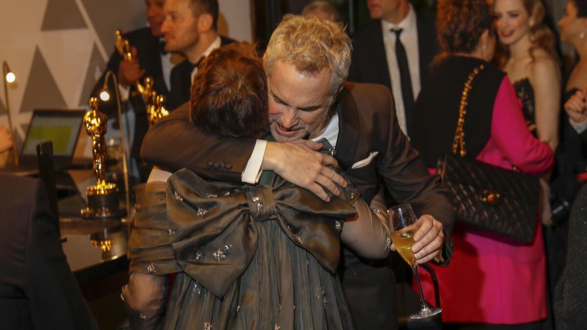 Alfonso Cuarón hugs lead actress winner Olivia Colman