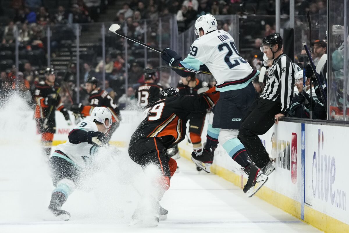 Seattle Kraken's Vince Dunn (29) leaps to avoid a check from Anaheim Ducks' Sam Carrick (39) during the first period of an NHL hockey game Sunday, Nov. 27, 2022, in Anaheim, Calif. (AP Photo/Jae C. Hong)