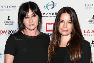 Holly Marie Combs and Shannen Doherty posing together in black outfits
