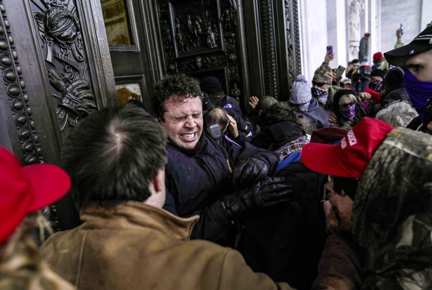 A man grimaces as he is squeezed up against the entryway to the Capitol building.