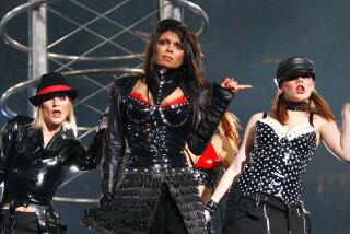 Janet Jackson and two female backup dancers perform