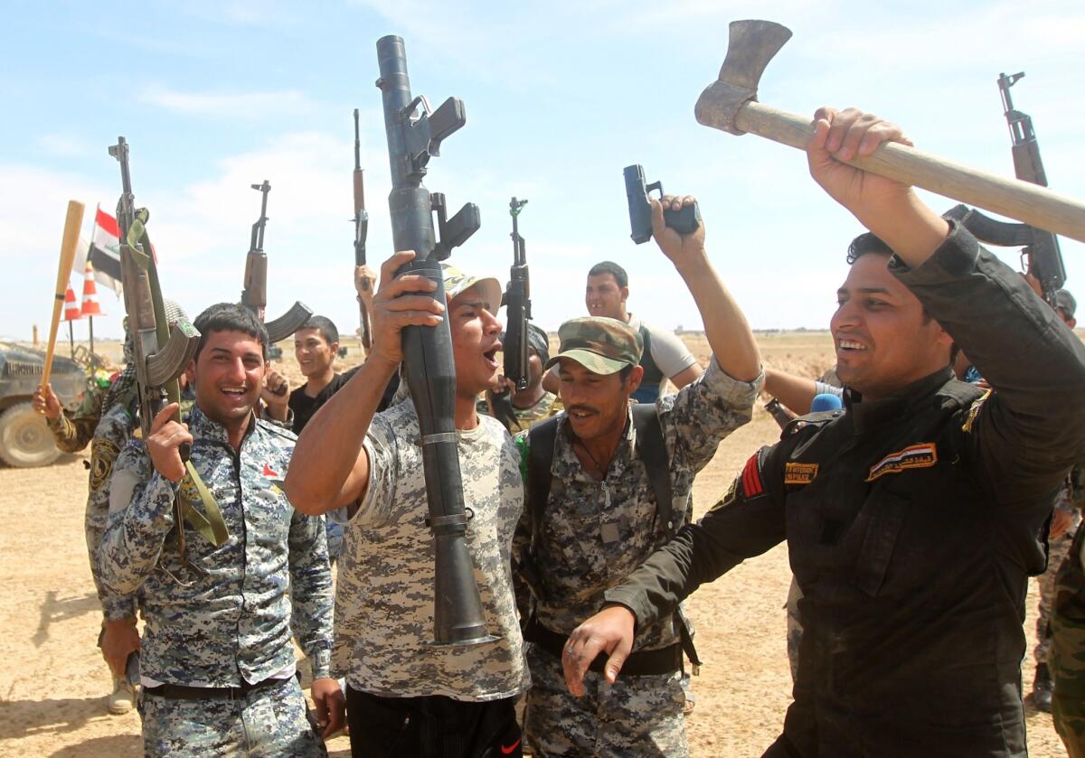 Iraqi government forces raise their weapons as they hold a position on the western outskirts of Tikrit on Friday.
