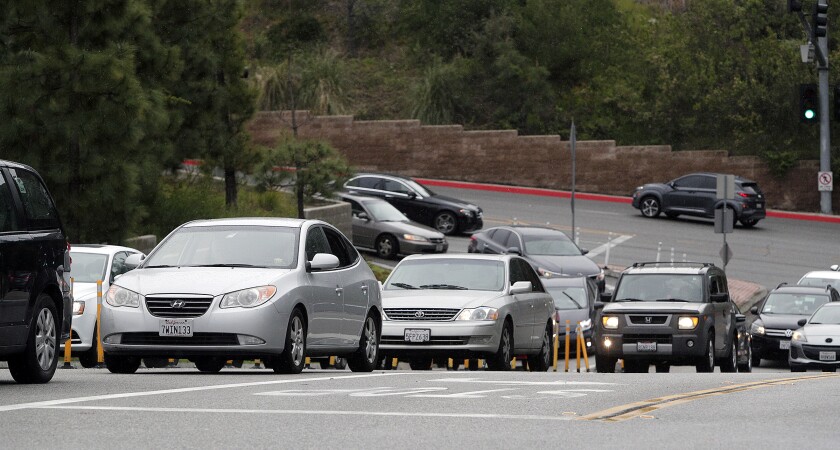 A line of vehicles backed up onto Mountain Street for the food bank at Glendale Community College on Tuesday. With GCC shut down due to the coronavirus, the campus food pantry was converted Tuesday into a mobile food pantry, not just for students but for anyone. Motorists backed up onto Mountain Street to turn onto College Driveway. In the college's parking structure, campus staff loaded vehicles with the donated food.
