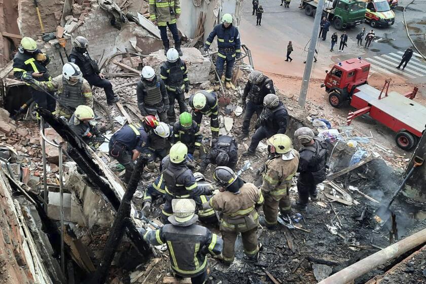 In this photo provided by the Ukrainian Police Press Office, emergency workers search for victims of the Russian rocket attack that damaged a multi-storey building in central Kharkiv, Friday, Oct. 6, 2023. (Ukrainian Police Press Office via AP)