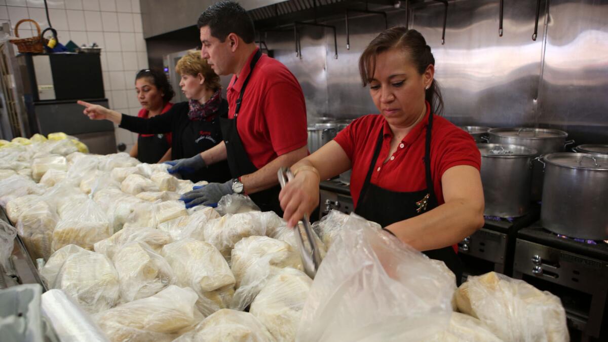 Lucy Garcia, right, and others make bags of holiday tamales for the Christmas Eve rush at Tamales Lilianas in East Los Angeles.