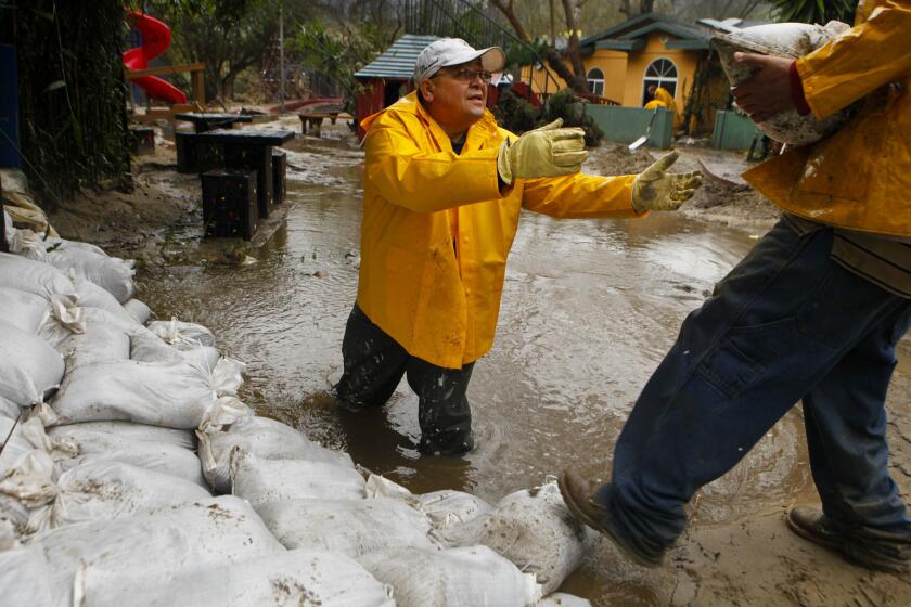 Staff member Manuel Celya stacks sandbags in the play yard at the Anneliese Schools' campus in Laguna Beach in an attempt to stem the flooding, December 29, 2010.