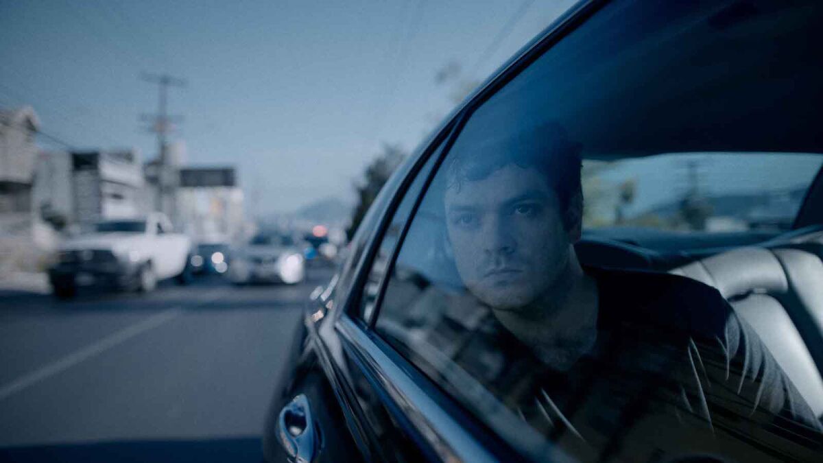 A man looks out of a car's backseat window.
