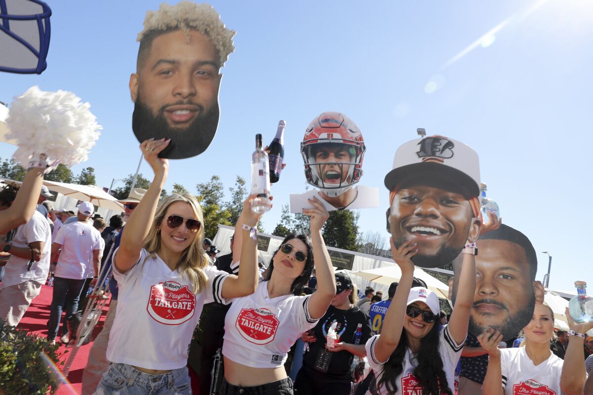 Women hold up cardboard cutouts of Odell Beckham Jr., Joe Burrow and Aaron Donald at the Players tailgate