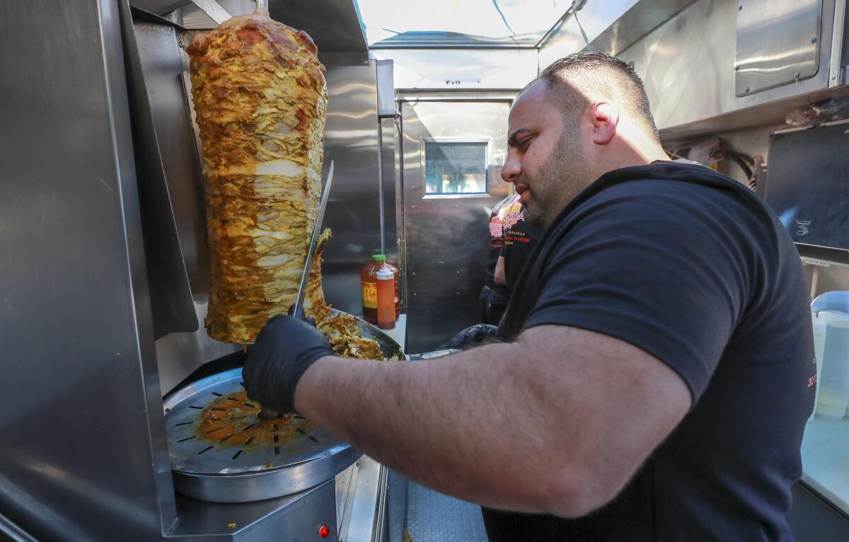 Bryan Zeto, owner and chef of the Shawarma Guys food truck, carves off chicken shawarma shavings in San Diego.
