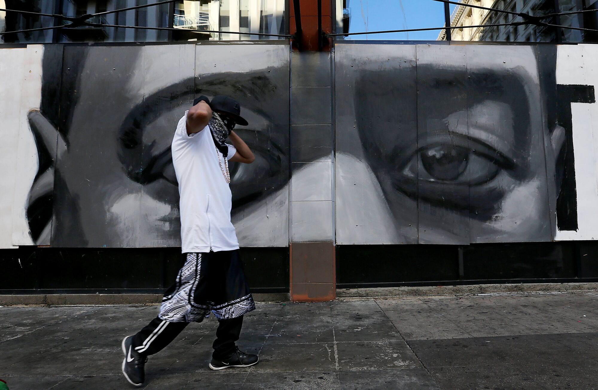 A man walks past a mural of George Floyd's eyes in downtown Los Angeles