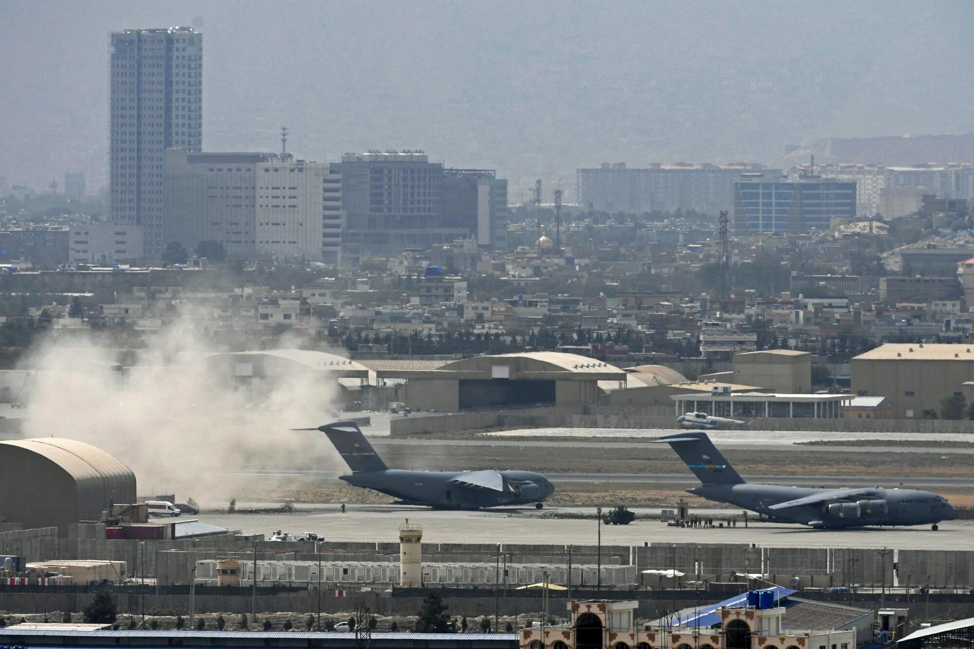 TOPSHOT - US soldiers stand on the tarmac as an US Air Force aircraftprepares to deaprt.