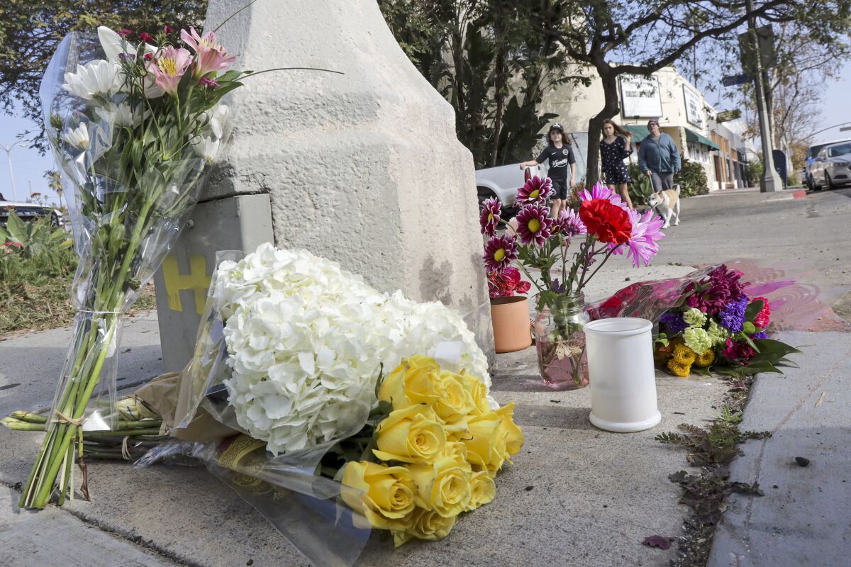 Bouquets of flowers at a makeshift memorial on the side of a street.