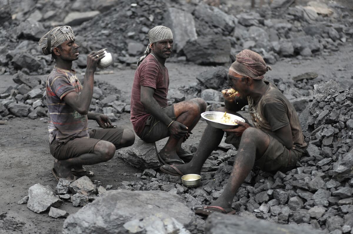FILE - In this Oct. 23, 2019, file photo, laborers eat lunch at a coal loading site in the village of Godhar in Jharia, a remote corner of eastern Jharkhand state, India. An energy crisis is looming over India as coal stockpiles grow perilously low, adding to challenges for a recovery in Asia's third largest economy from the pandemic. Supplies at the majority of coal-fired power plants in India have dwindled to just days worth of stock. (AP Photo/Aijaz Rahi, file)