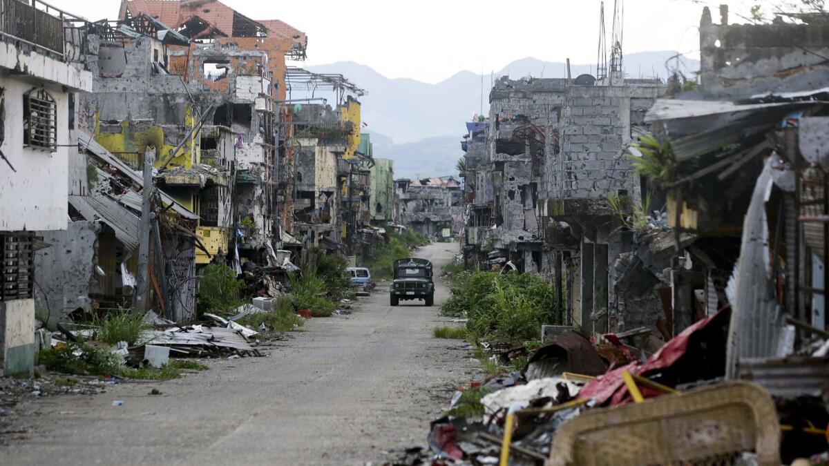 A military vehicle passes by ruins in Marawi, southern Philippines.