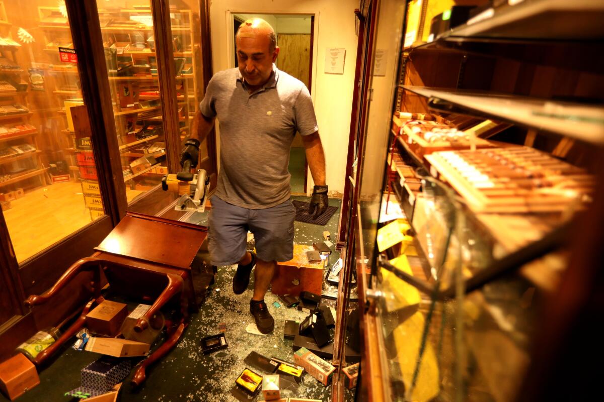Santa Monica Tobacco owner Moe T. walks through his store Monday, the day after intruders smashed cases and stole items.