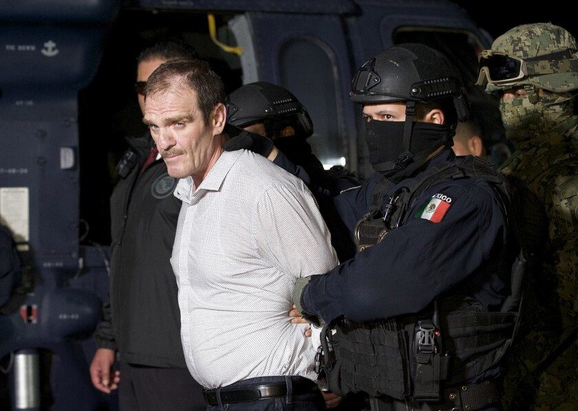 FILE - In this June 15, 2016 file photo provided by the Mexican Attorney General's Office, Hector "El Guero" Palma, or “Blondie,” one of the founders of the Sinaloa Cartel, is escorted in handcuffs from a helicopter at a federal hangar in Mexico City, after serving almost a decade in a U.S. prison and transported to another maximum-security lockup to await trial for two murders. (Mexico's Attorney General's Office via AP, File)