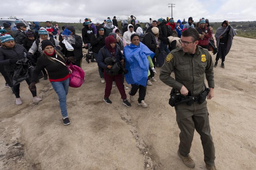 Solicitantes de asilo, incluido un grupo de peruanos, caminan detrás de un agente de la Patrulla Fronteriza hacia una camioneta después de cruzar la frontera desde México, el 25 de abril de 2024, en Boulevard, California. (AP Foto/Gregory Bull, Archivo)