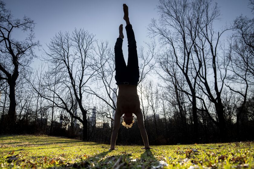 Marco Amantini does a handstand in the grass near the Great Lawn at the center of Central Park, Monday, Jan. 30, 2023, in the Manhattan borough of New York. Since the start of winter in December, there hasn't been any measurable snowfall in the city. The last time it took this long before snow lingered on the ground in the wintertime was 1973, when New Yorkers had to wait until Jan. 29. (AP Photo/John Minchillo)