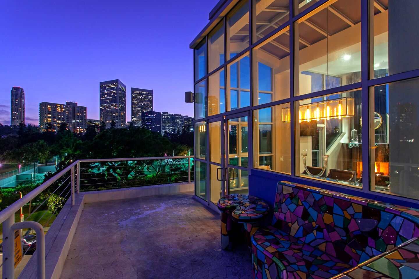 The offbeat penthouse in Beverly Hills was designed in the 1980s by noted architect Frank Gehry for a commercial illustrator. Gehry's influences can be seen in the home's unusual shapes and forms, which were designed to evoke a small city. The patterned tilework and splashes of color are a reflection of the original owner's love of pottery and mosaics. A tiled bathroom was recently restored in keeping with the original vision. Walls in certain rooms have been swapped for expanses of glass. The fireplace in the master bedroom was inspired by a ziggurat and features small steps leading up towards the heavens.