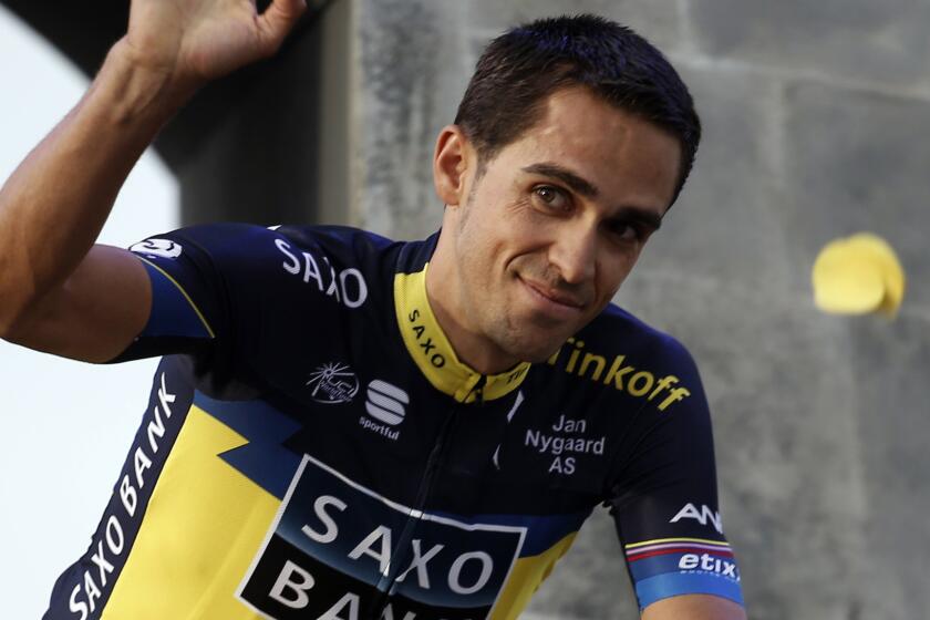Alberto Contador waves while riding to a presentation ceremony in Corsica on June 27, 2013.
