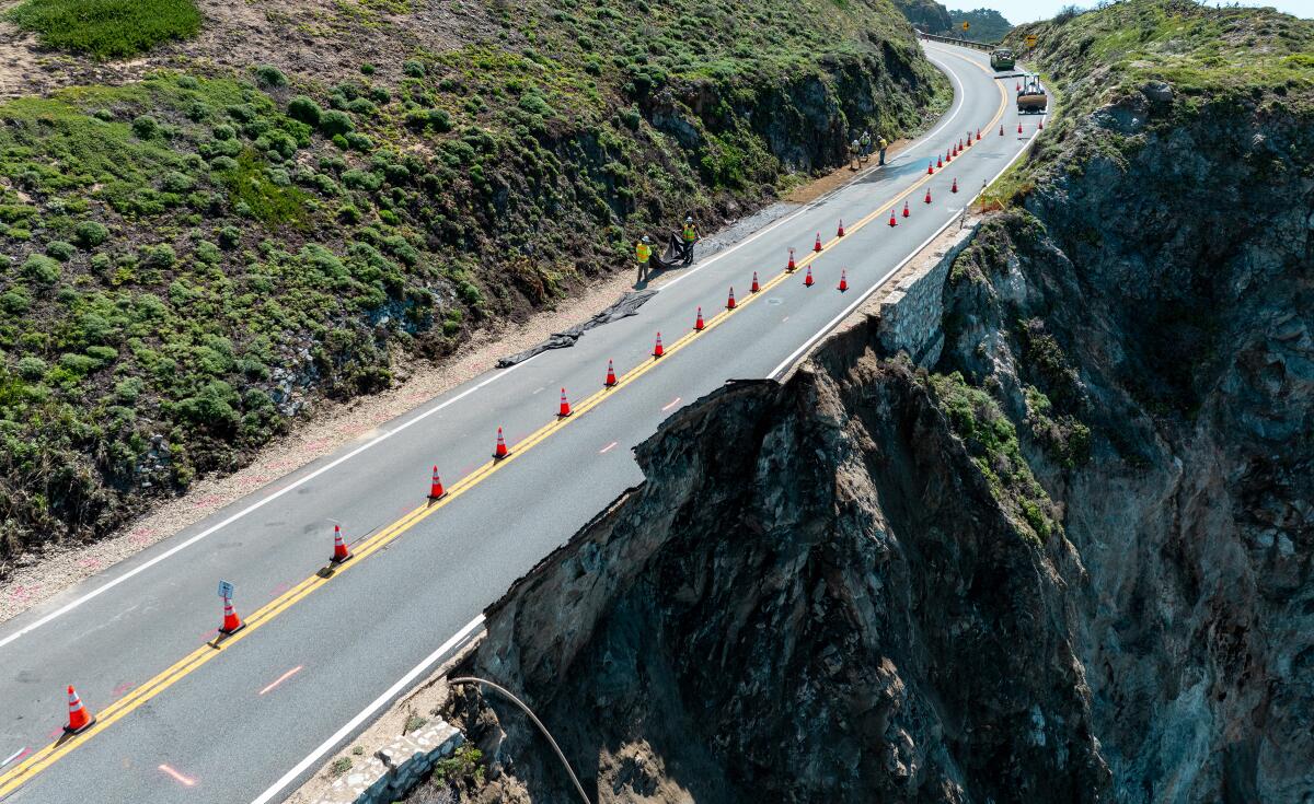 A roadway on a cliff's edge with orange cones along its center divider