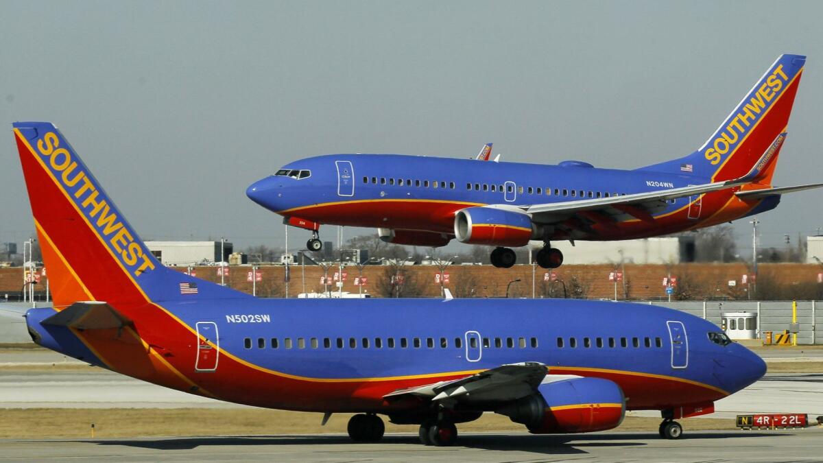A Southwest Airlines Boeing 737 waits to take off at Chicago's Midway Airport as another lands. The Dallas-based carrier plans to begin selling tickets to flights to four airports in Hawaii later this year from Oakland, San Diego, San Jose and Sacramento.