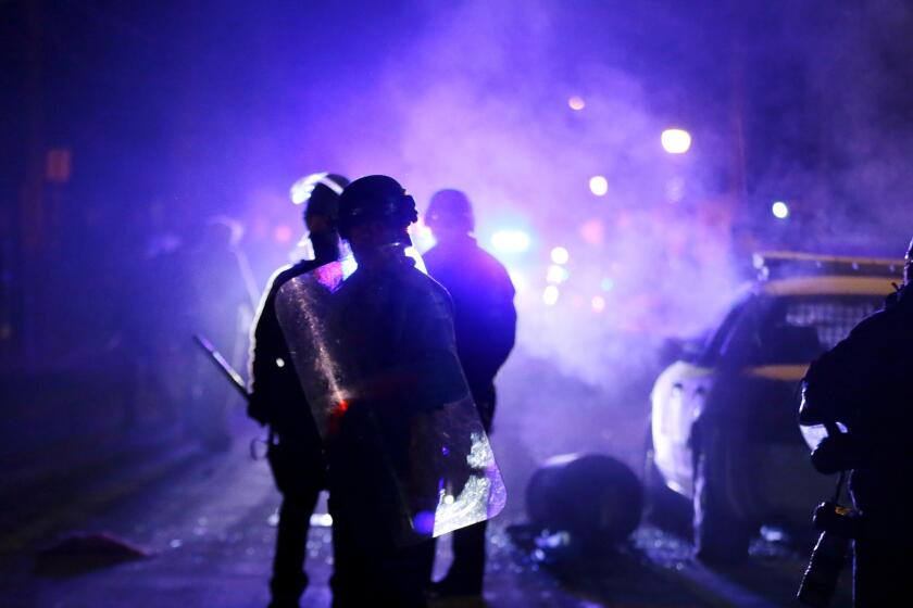 Police officers watch protesters as smoke fills the streets in Ferguson, Mo., in November 2014.