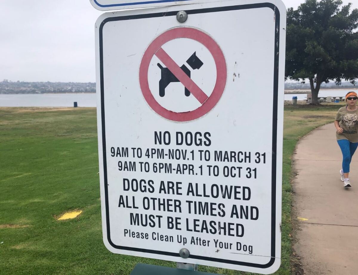 A sign shows the hours that dogs are not allowed at Mission Bay parks.