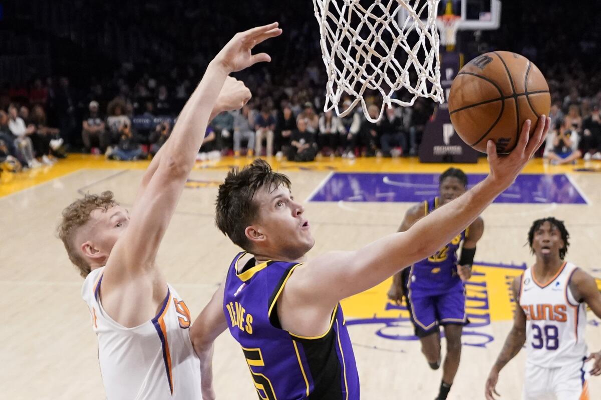 Lakers guard Austin Reaves attempts a reverse layup as he glides past Suns center Jock Landale.