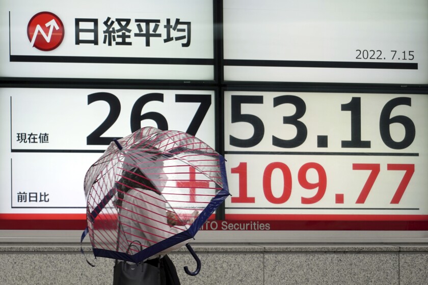 A person wearing a protective mask walks in front of an electronic stock board showing Japan's Nikkei 225 index at a securities firm Friday, July 15, 2022, in Tokyo. Share prices were mixed in Asia on Friday after China reported its economy contracted by 2.6% in the last quarter as virus shutdowns kept businesses closed and people at home. (AP Photo/Eugene Hoshiko)