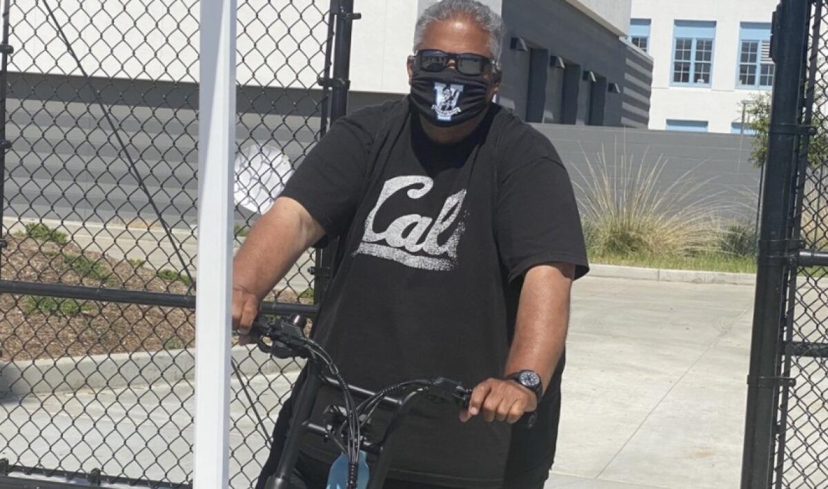 Angelo Gasca wears a mask and holds the handlebars of a bike.