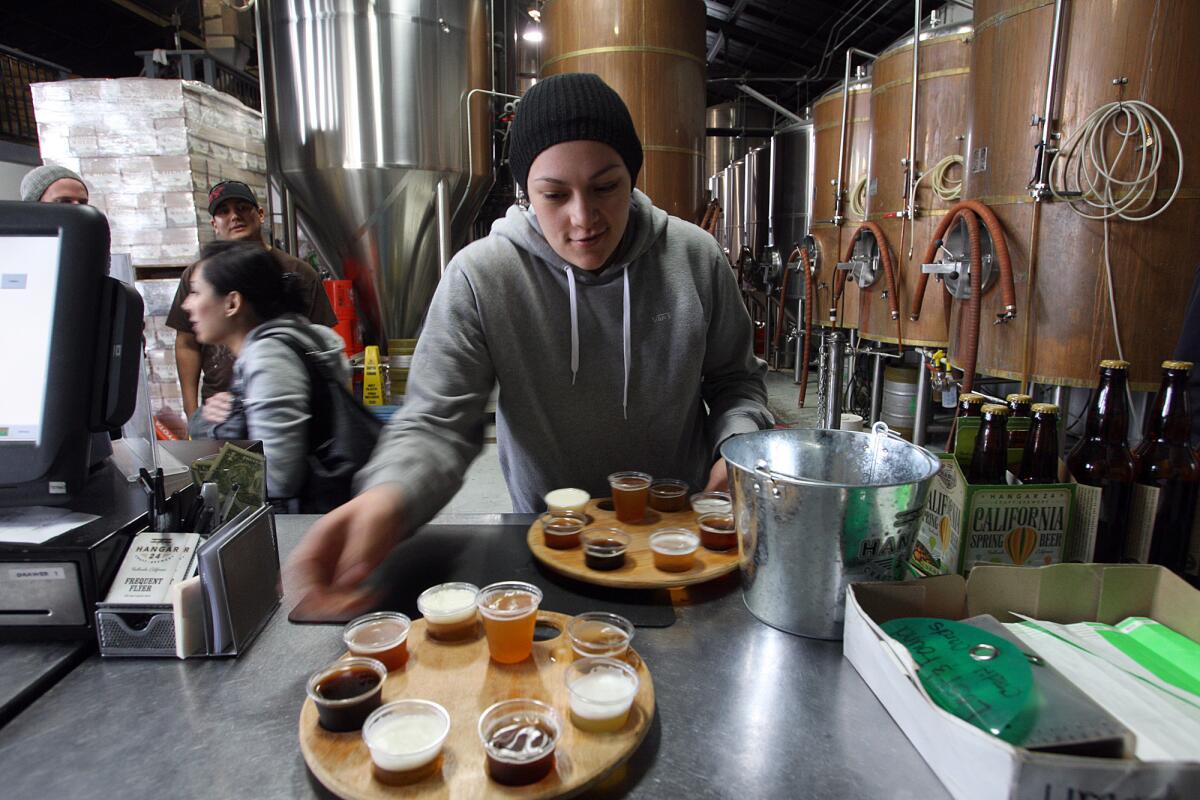 Monica Kyle grabs sampler trays at Hangar 24, which is celebrating its birthday this weekend.