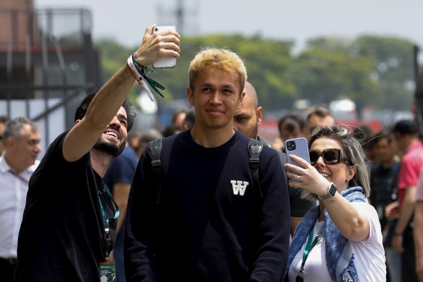 FILE - Fans take photos with Williams driver Alex Albon, of Britain, as he arrives to Interlagos racetrack for practice ahead of the weekend's Formula One Brazilian Grand Prix in Sao Paulo, Brazil, Nov. 11, 2022. Williams driver Alex Albon intends to show the more steely side to his personalty in Formula One. The affable Albon is one of the most popular drivers but thinks that also comes with some misperception. He says people "see me as a happy-go-lucky person" but “I’m much stronger than people can imagine.” (AP Photo/Marcelo Chello, File)