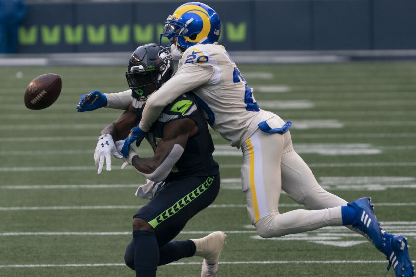 Los Angeles Rams defensive back Jalen Ramsey knocks the ball asway from Seattle Seahawks wide receiver DK Metcalf during the first half of an NFL football game, Sunday, Dec. 27, 2020, in Seattle. (AP Photo/Stephen Brashear)