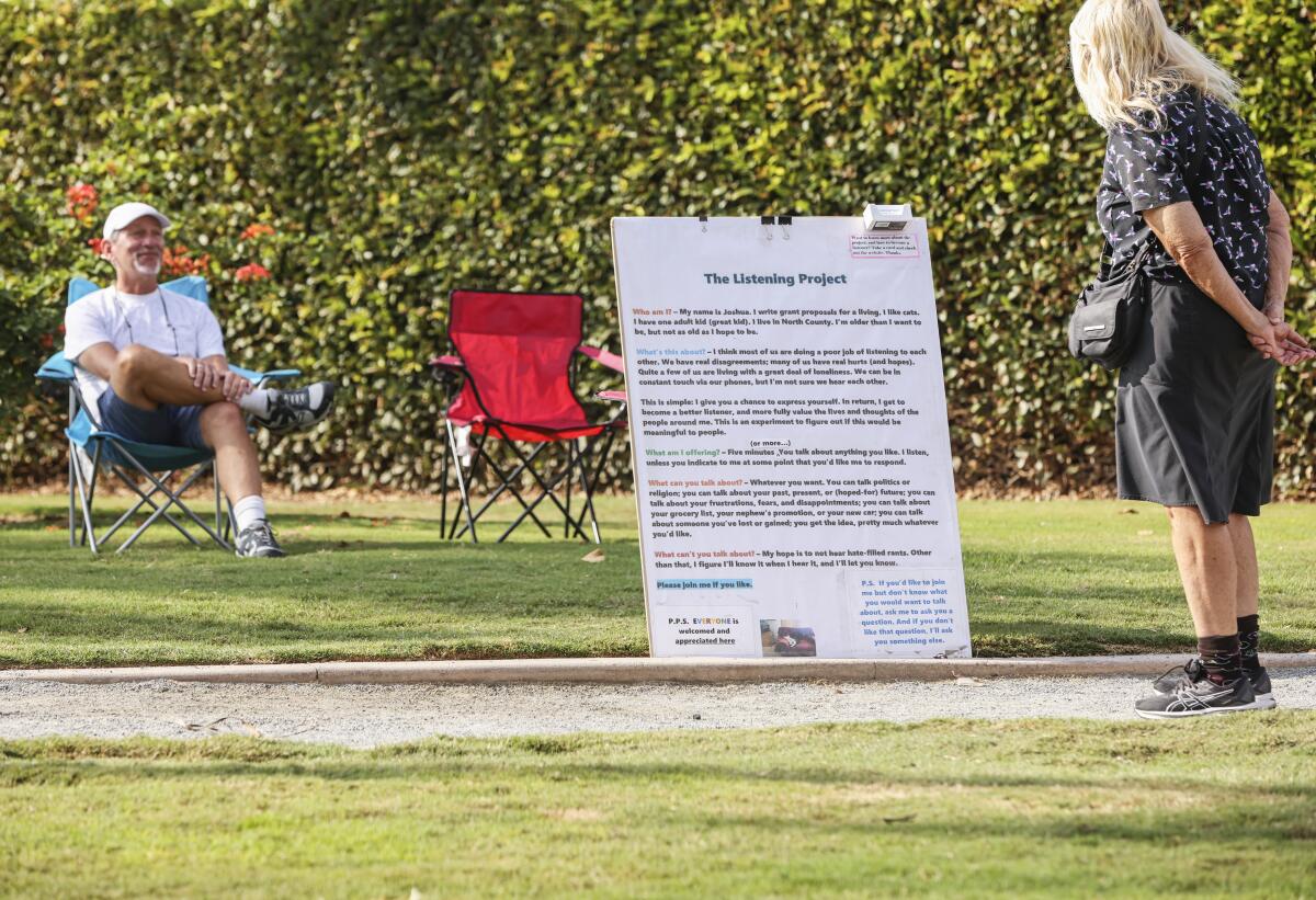 Joshua Lazerson, left, watches Sara Ohara reads his Listening Project sign at Swami's Seaside Park in Encinitas.