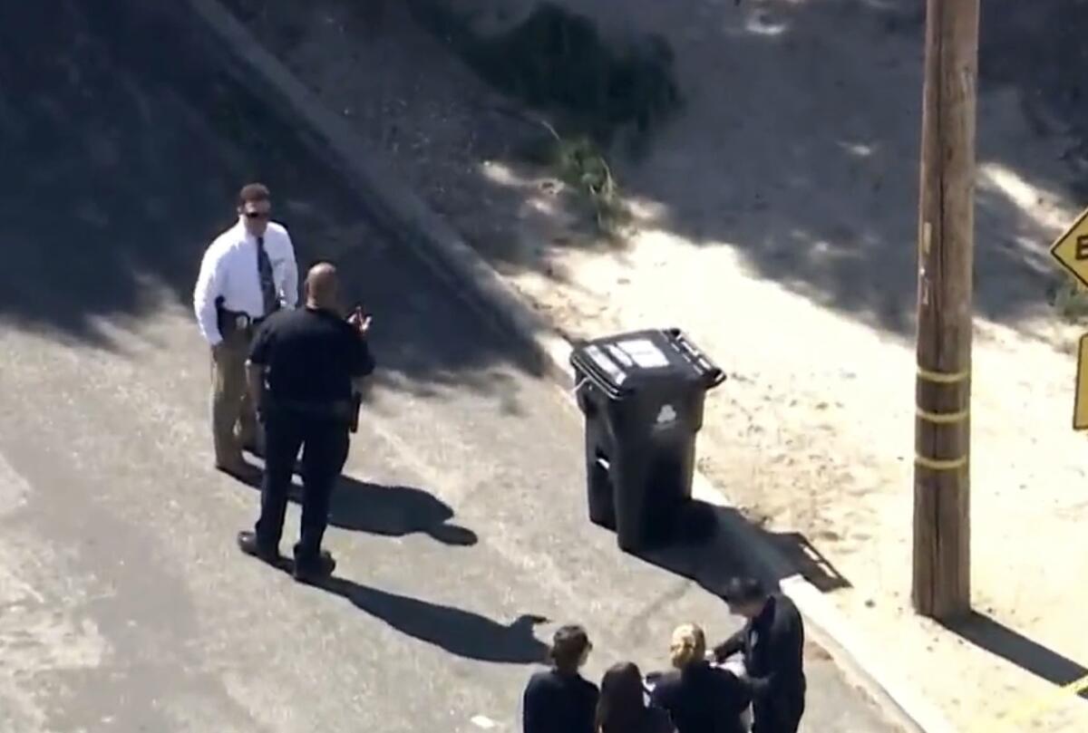Police officers investigate a body found inside a trash can in Sunland. 