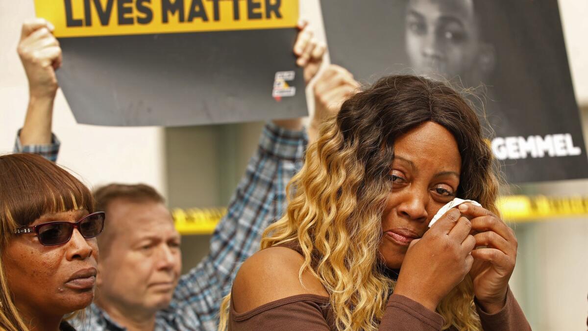 LaTisha Nixon, with a photo of her son, Gemmel Moore, behind her, cries during a news conference announcing a petition with 30,000 signatures calling for the prosecution of Ed Buck.