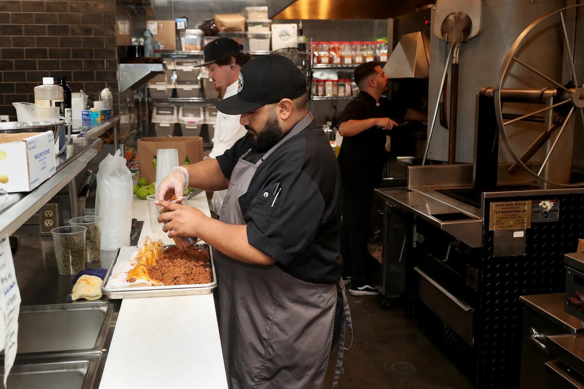 Sous chef Ruben Jaimes fills plastic containers with red and green chorizo at Chaak Kitchen in Tustin.