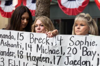 (L-R) Lisa Pearson, Victoria Hinks and Lori Schott hold a banner displaying names of people