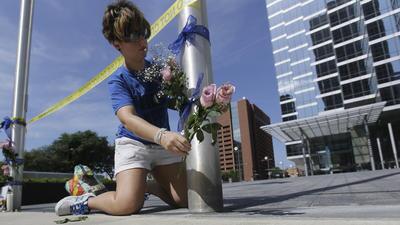 Noelle Hendrix places flowers near the scene of the shooting in downtown Dallas.