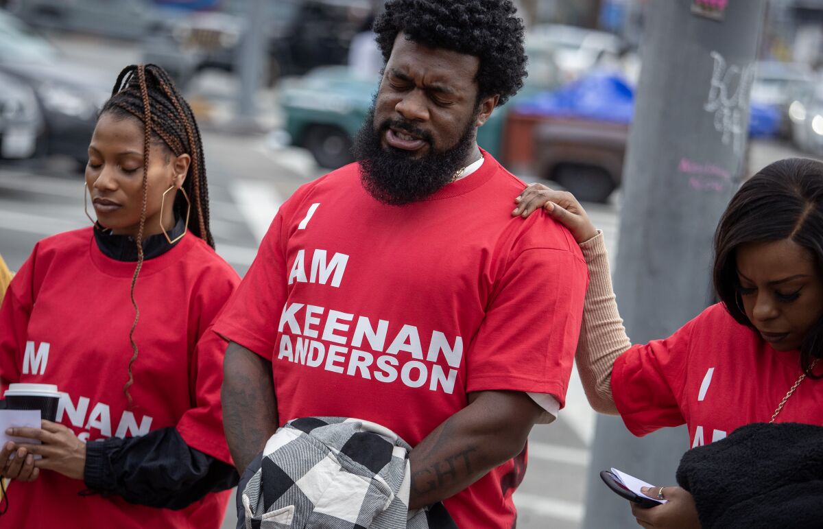 A Black man in a red 'I Am Keenan Anderson' T-shirt leads a prayer before marching to Frieze Los Angeles.