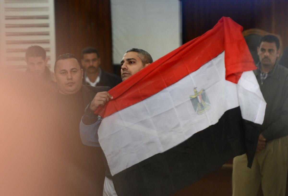 Al Jazeera journalist Mohamed Fahmy holds the Egyptian flag at a court hearing in Cairo on Feb. 12.