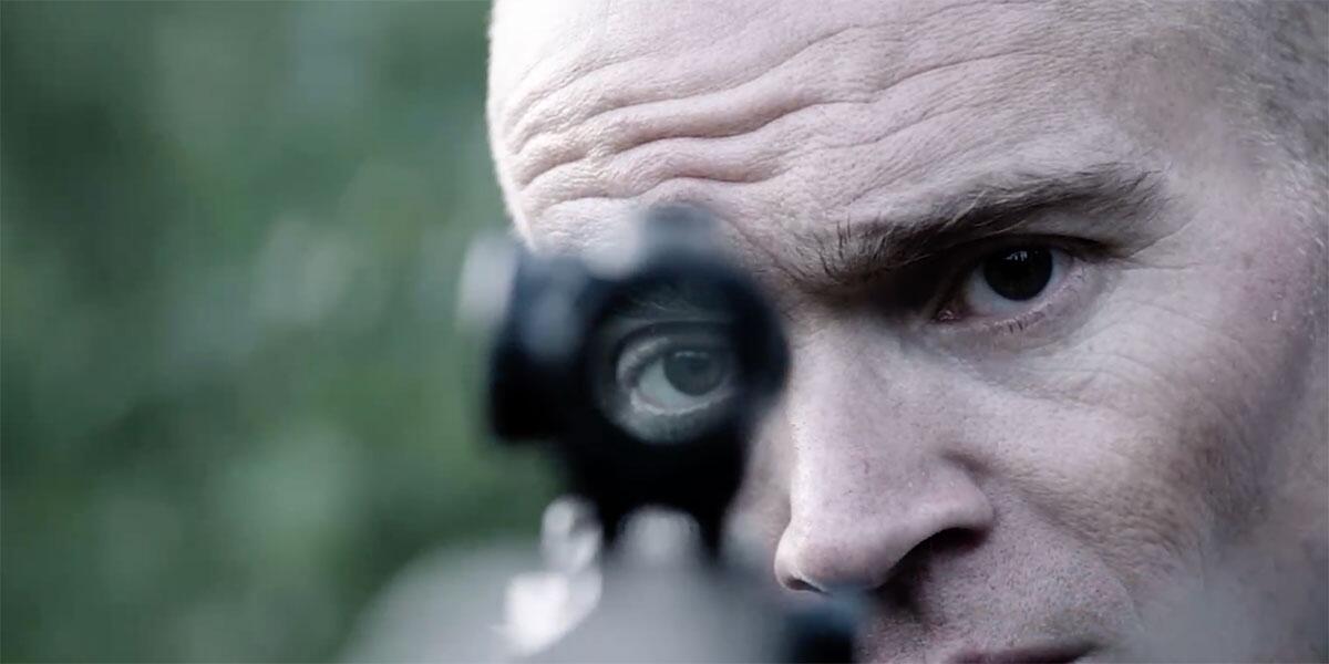 A man looks through the sight of a sniper rifle.