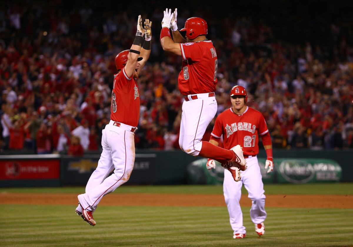 Angels outfielder Kole Calhoun, left, and Albert Pujols, center, share a leaping double high-five to celebrate Pujols' game-winning hit while Mike Trout (27) looks on.