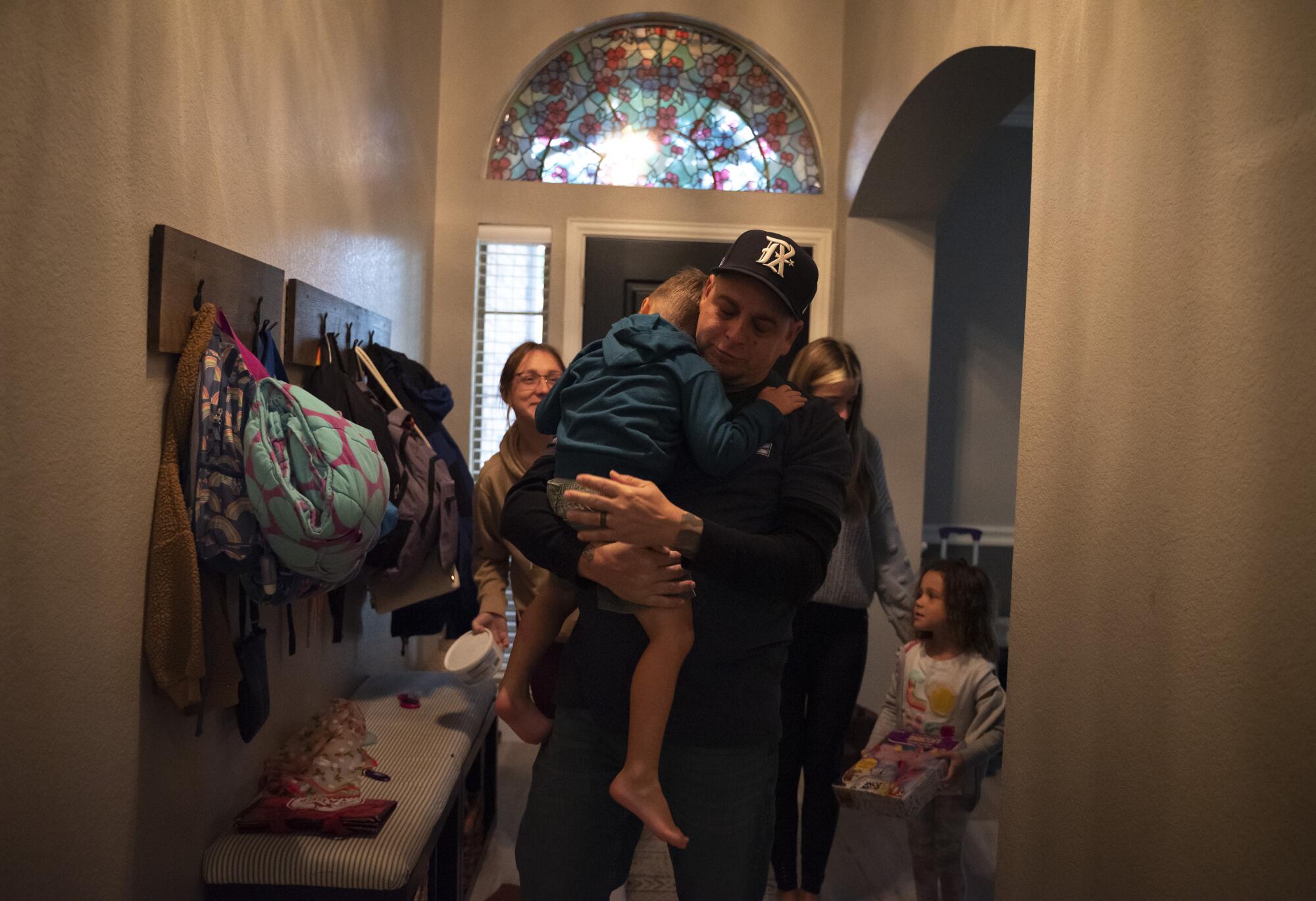 A man holds a child in his arms as three other people stand near them.