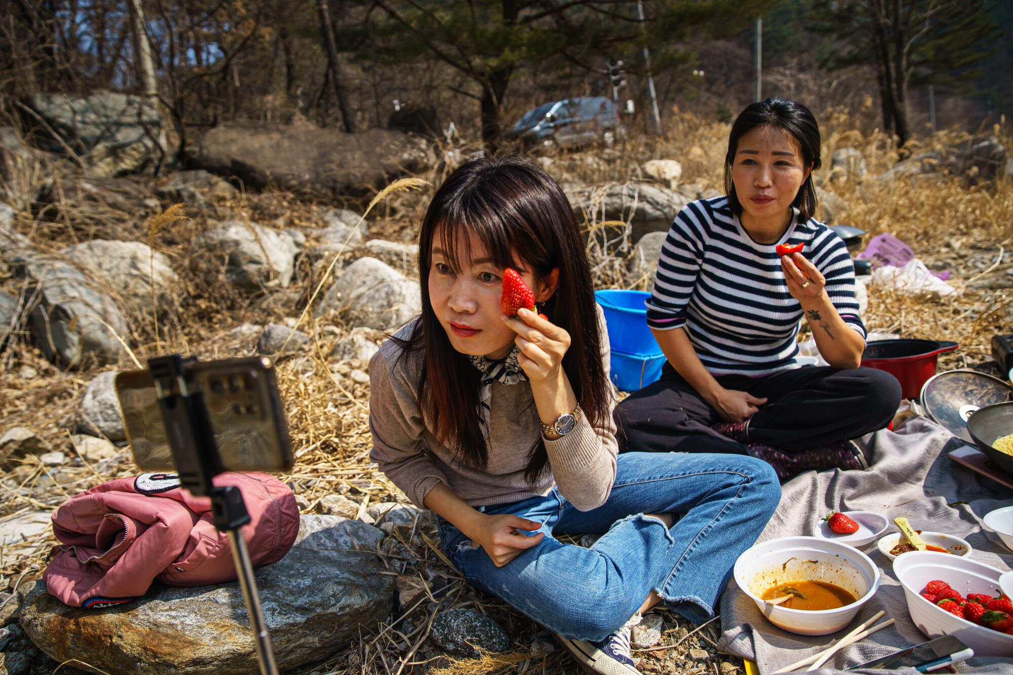 Sim Ha Yoon, left and Seok Hyeon Ju, right, hold up strawberries during a picnic