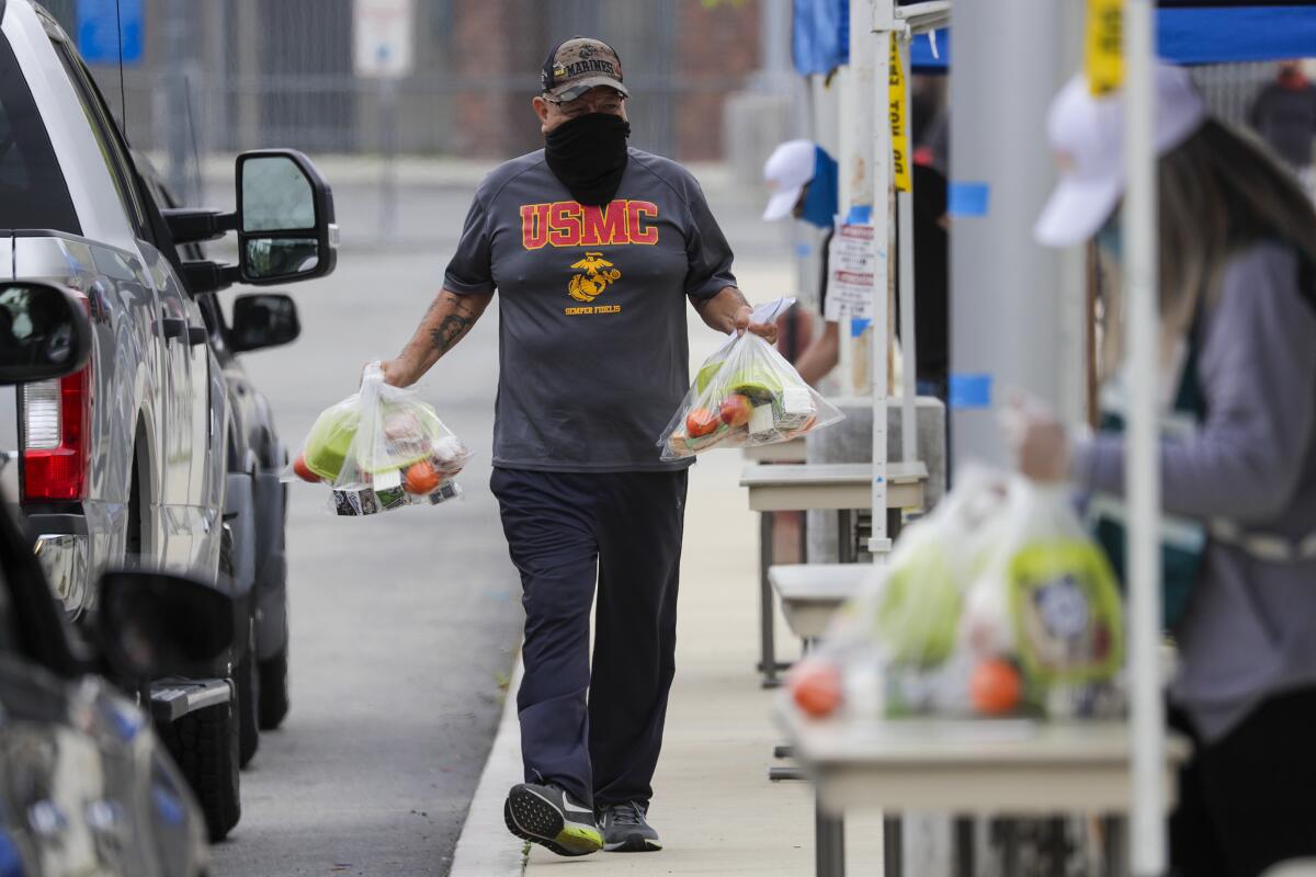 Un padre recoge paquetes provistos por LAUSD en un centro de comida para llevar en Byrd Middle School.
