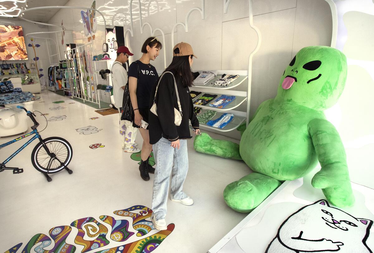 Two people look at a large stuffed alien toy in a store.