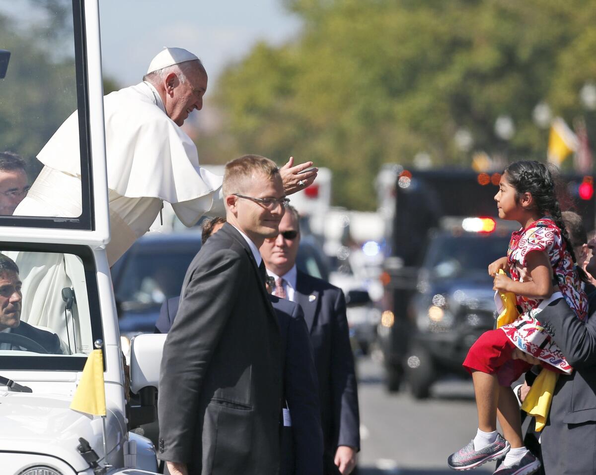 Pope Francis reaches for Sophie Cruz, the daughter of two immigrants in the country illegally, during a parade in Washington last September.