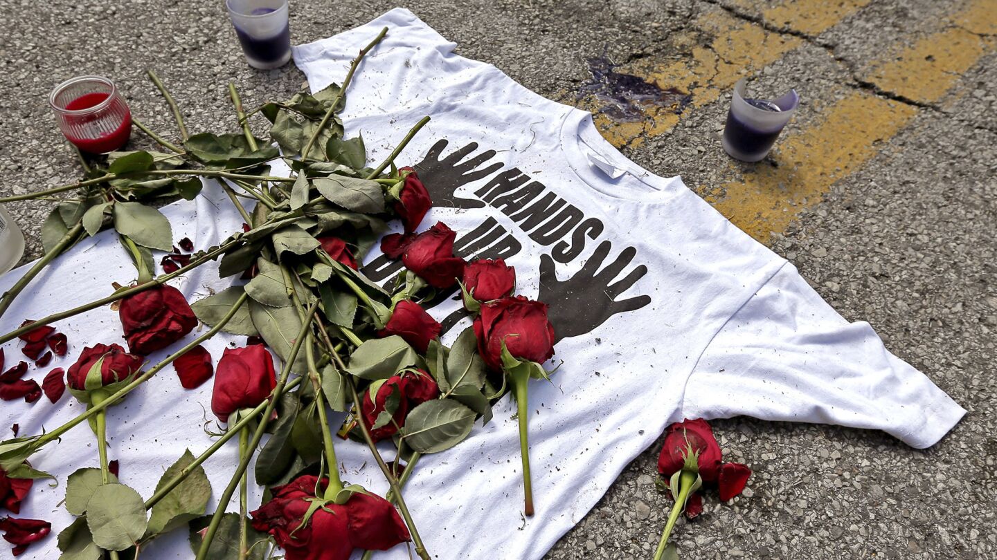 A shirt reading "hands up don't shoot" is covered with roses Tuesday at the spot Michael Brown was killed by police Aug. 9 in Ferguson, Mo.